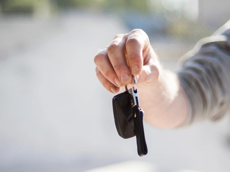A hand holding out a set of car keys